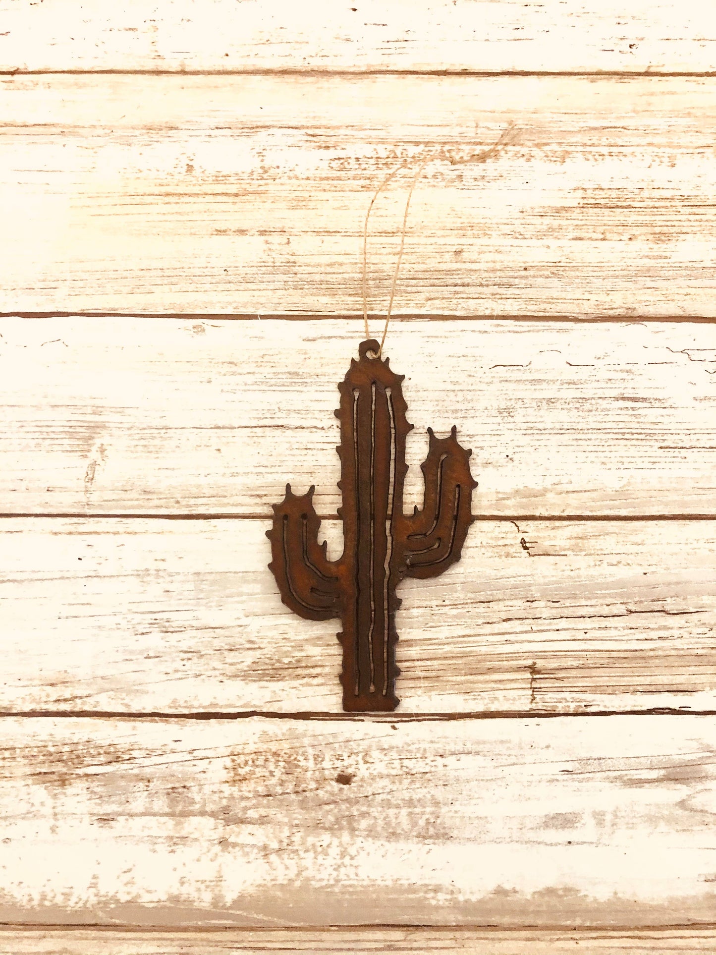 A brown metal cactus-shaped ornament on a wooden background.